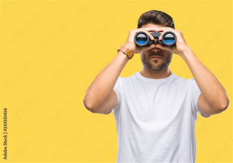 Young Handsome Man Looking Through Binoculars Over Isolated Background