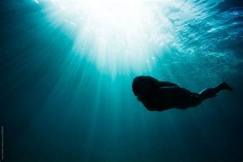 Girl Swimming Under Water In The Ocean As The Sun Rays Shine Down By Stocksy Contributor Gary