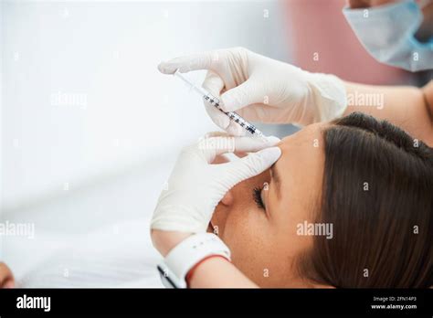 Woman Getting A Dermal Filler Injection Into The Glabellar Line Stock