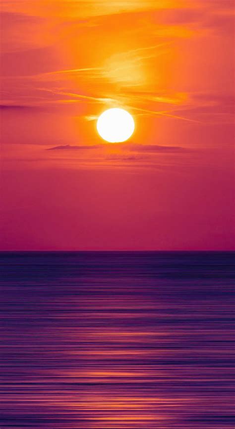 The Sun Is Setting Over The Ocean With Purple And Orange Hues In The Sky