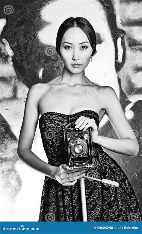 femme asiatique de foto dans la robe avec les épaules nues et le vieil appareil photo photo