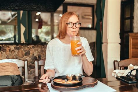 Young Cheerful Woman Drinking Healthy Carrot Smoothie In Cafe Stock