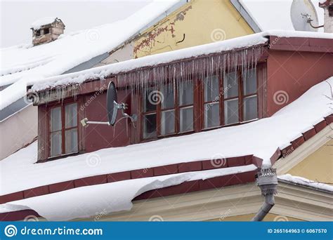 Icicles And Snow On The Roof Of The House On A Snowy Winter Day Among