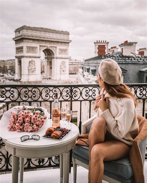 A Woman Sitting At A Table With Food And Drinks In Front Of The Arc De Trioe