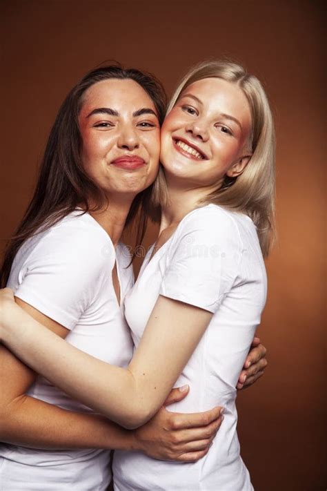 Two Pretty Diverse Girls Happy Posing Together Blond And Brunette On Brown Background