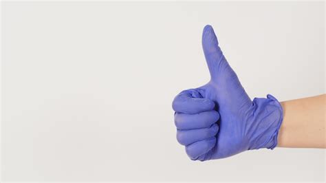 A Mão Está Usando Uma Luva De Látex Violeta Ou Roxa E Gosta De Handsign Em Fundo Branco Foto