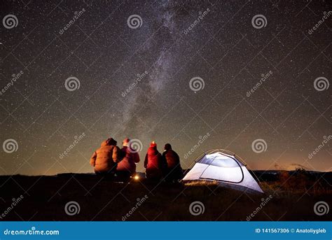 Friends Resting Beside Camp Campfire Under Night Starry Sky Stock