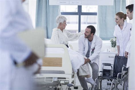 Doctor And Staff Helping Patient With Wheelchair In Hospital Stock Photo
