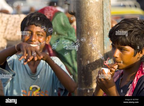 A Young Indian Boy Laughing Trying To Catch The Bubbles Blown By His