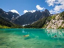 two people in kayaks floating on the water near mountains