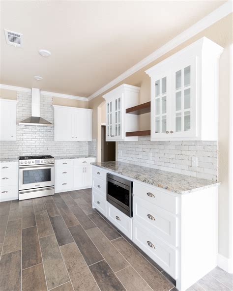 The primary reason why people want a change in the kitchen is because of dirty grout. White kitchen with stained floating shelves, wood look ...