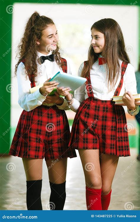 Two Pretty Schoolgirls In School Uniform Stand With Books Stock Image