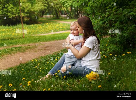 Young Pregnant Girl Sits On Lawn In City Park Mother Hugs And Kisses