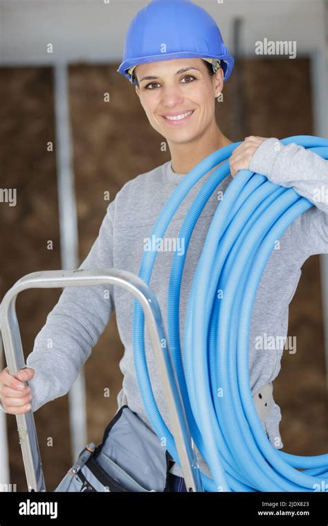 Female Builder On Stepladder Holding Blue Pipe Stock Photo Alamy