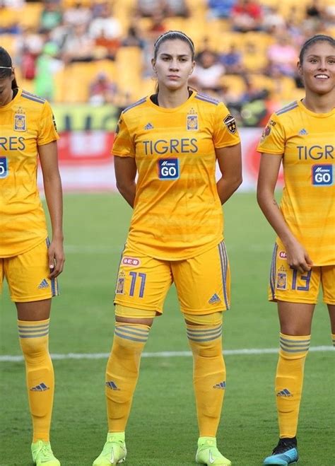 Three Women In Yellow Soccer Uniforms Standing On The Field