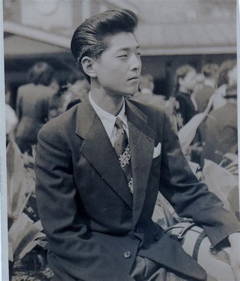 An Old Black And White Photo Of A Man In A Suit Sitting On The Ground