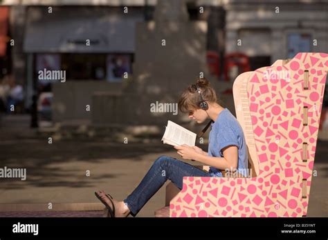 Young Girl Reading Book And Listening To Music On Sloane Square Chelsea