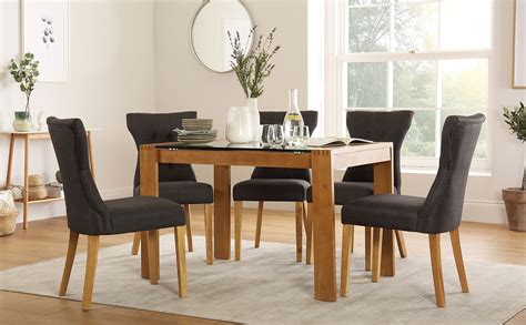 A round glass dining room table with a rich, dark finish. Tate 120cm Oak and Glass Dining Table with 6 Bewley Slate ...
