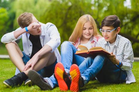 Smiling Kids Having Fun And Reading Book At Grass Children Playing