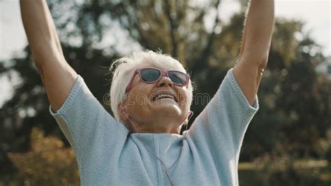 Cool Grandmother With Pink Sunglasses And Headphones Stretching In The