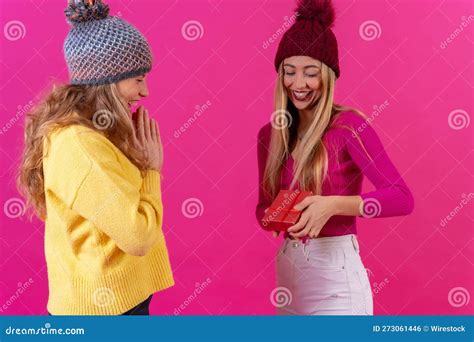 Joyful Young Female Friends Embracing Each Other While Holding A T Box With A Big Red Bow