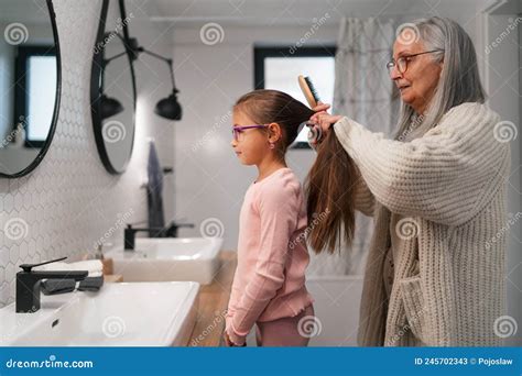 Senior Grandmother And Granddaughter Standing Indoors In Bathroom