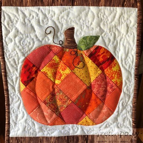 An Orange Quilted Pumpkin Sitting On Top Of A Piece Of Cloth In Front