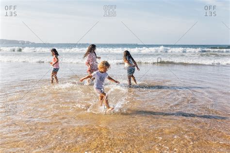 Four Children Splashing With Water At Seaside Stock Photo Offset