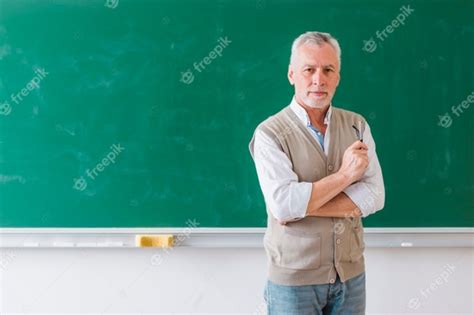 Senior Male Professor Standing Against Green Chalkboard Photo Free