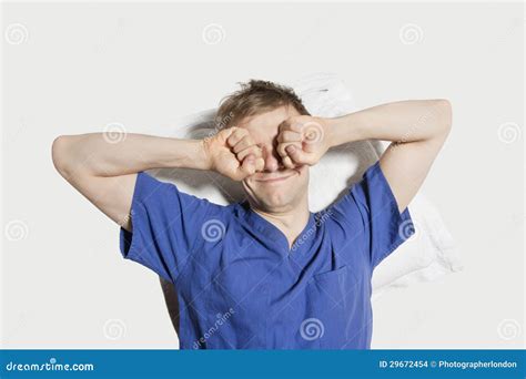 Young Man Rubbing Eyes While Waking Up Over Colored Background Stock