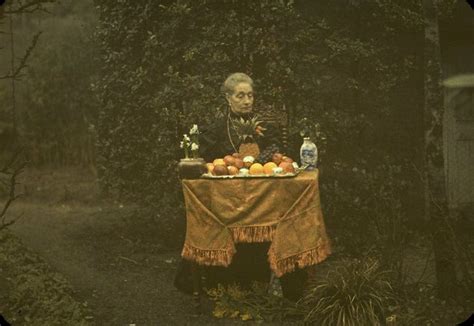 An Old Woman Sitting At A Table With Fruit On It