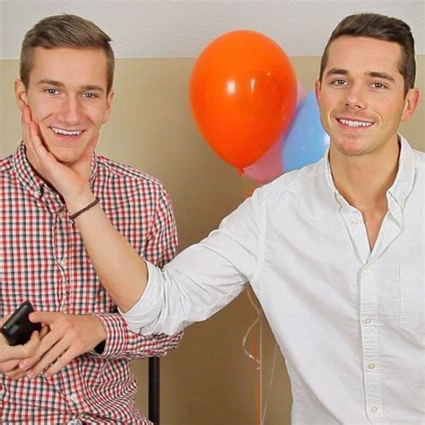 Two Men Standing Next To Each Other With Balloons And Cell Phones In