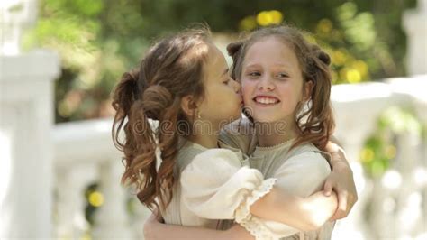 Two Sisters Cuddle Each Other Close Up Smaller And Older Girls Rub Their Noses Sisters