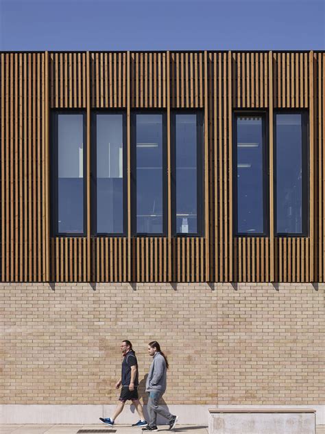 Two People Walking Down The Sidewalk In Front Of A Building With Wooden