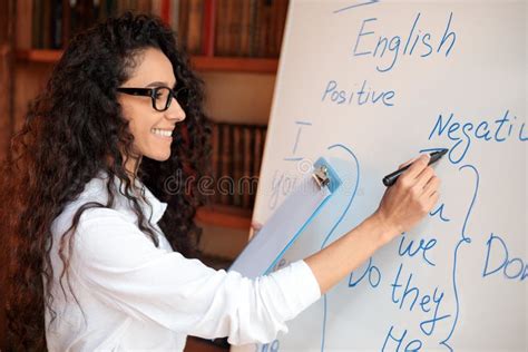 English Teacher Writing At Whiteboard Explaining Rules To The Students