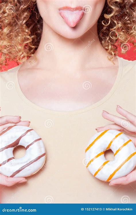 Beautiful Young Cheerful Girl Shows Tongue And Holds Donuts In Front Of Breasts Stock Image