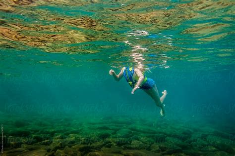 underwater girl swimming in summer lake wearing lifejacket by stocksy contributor jp danko