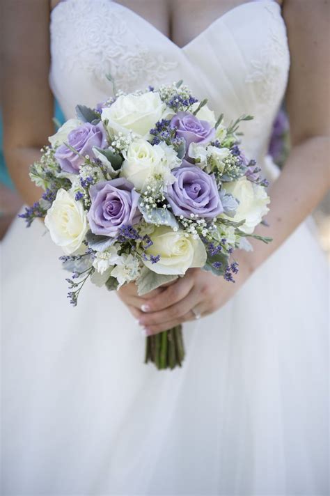 The Bride Is Holding Her Purple And White Bouquet