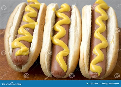 Tasty Hot Dogs With Yellow Mustard On Wooden Board On Grey Background
