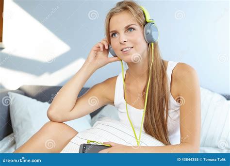 Woman Lying On Bed While Listening Music Through Headphone Stock Image