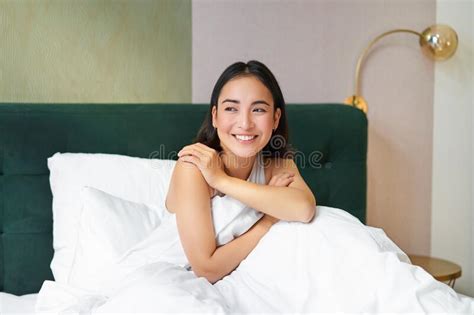 Happy Mornings Smiling Asian Woman Wakes Up In Her Bed Looks Outside