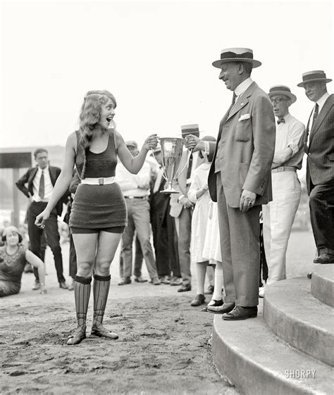 A Man And Woman Standing Next To Each Other In Front Of A Group Of People