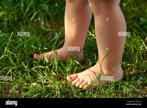 The Feet Of A Small Child On The Grass Walking On Bumps The