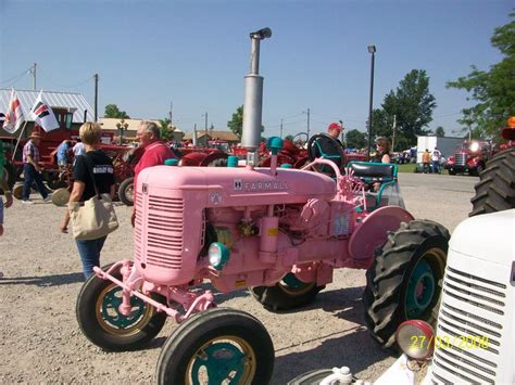 An Old Pink Tractor Is Parked In The Dirt