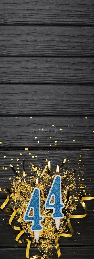 Number 44 Blue Celebration Candle And Gold Confetti On Dark Wooden