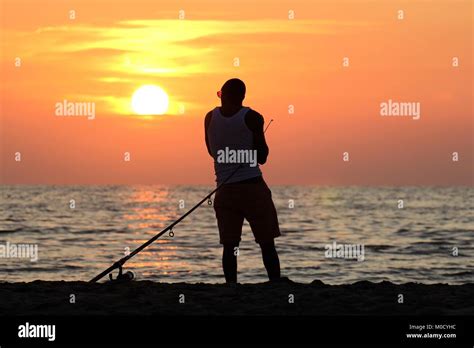 Fisherman At Sea Against Sunset Stock Photo Alamy