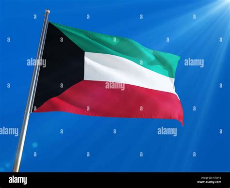 Kuwait National Flag Waving On Pole Against Deep Blue Sky Background
