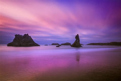 Rock Formation Surrounded With Body Of Water Under Blue And Pink Sky