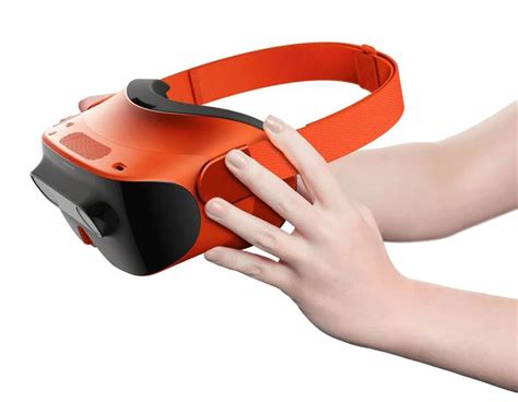 A Person Holding An Orange Virtual Reality Device In Their Left Hand