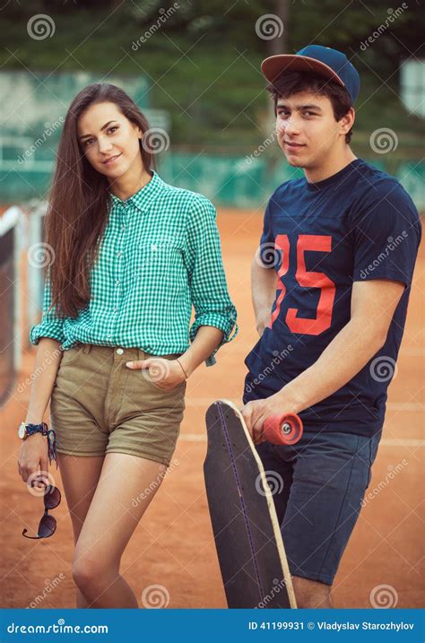 Young Couple Standing On A Skateboard On The Tennis Court Stock Image